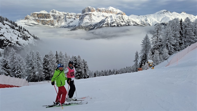 Francesco e Silvia coon gli sci ai piedi incorniciati da un paesaggio di monti innevati.